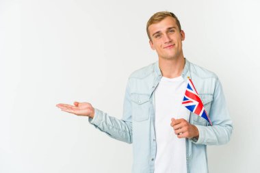 Beyaz arka planda izole edilmiş bir krallık bayrağı tutan genç beyaz bir adam bir avuç içinde fotokopi alanı ve belinde başka bir el tutuyor..