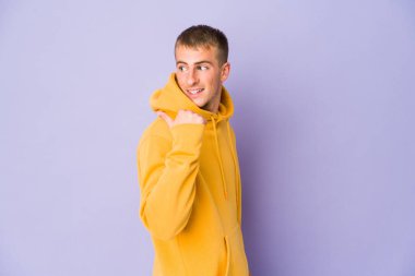 Beyaz tenli yakışıklı adam başparmağıyla işaret ediyor, gülüyor ve kaygısız..