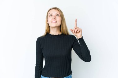Beyaz arka planda izole edilmiş genç sarışın kadın iki parmağı da boş bir alan gösteriyor..