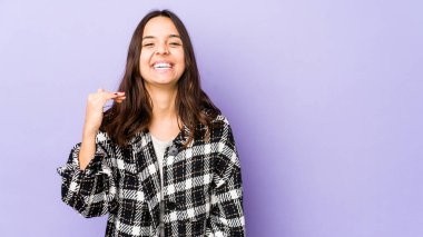 Latin kökenli genç bir kadın bir şeylere gülüyor, elleriyle ağzını kapatıyor..