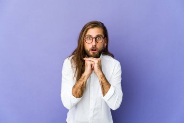 Uzun saçlı genç adam şans için dua ediyor, şaşırmış ve ağzını açıyor..