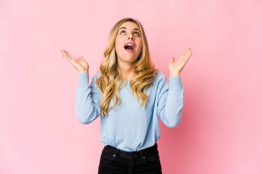 Genç, beyaz, sarışın kadın kameraya parmaklarıyla göz kırpıyor, yüzünü kapatmaktan utanıyor..