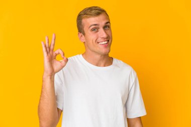 Beyaz tenli yakışıklı bir adam göz kırptı ve elleriyle iyi bir jest yaptı..