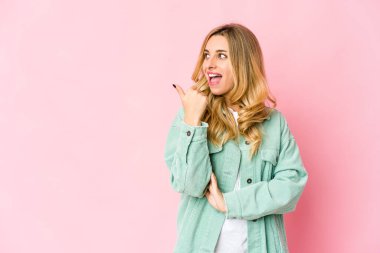 Beyaz tenli sarışın kadın başparmağıyla işaret ediyor, gülüyor ve kaygısız..