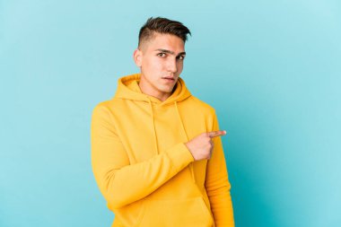 Beyaz tenli yakışıklı, izole edilmiş gülümseyen ve işaret eden, boş alanda bir şeyler gösteren bir adam..