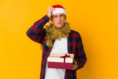 Sarı arka planda izole edilmiş bir hediye tutan Kafkasyalı genç adam amaçlarına ve amaçlarına ulaşma hayali kuruyor.