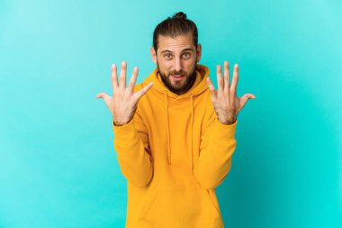 Uzun saçlı genç adam on numarayı elleriyle gösteriyor..