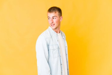 Genç beyaz yakışıklı adam gülümseyen, neşeli ve keyifli bir şekilde yana bakıyor..