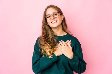 Genç beyaz kadın gülüyor, ellerini kalbe koyuyor, mutluluk kavramı..