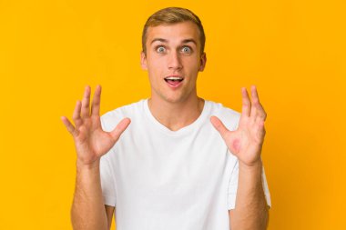 Genç beyaz yakışıklı adam hoş bir sürpriz yapıyor, heyecanlı ve el kaldırıyor..