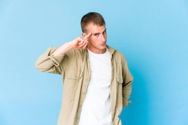 Genç, beyaz, yakışıklı bir adam şakağı parmağıyla işaret ediyor. Düşünüyor, bir göreve odaklanıyor..