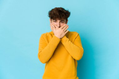 Mavi arka plandaki genç Arap adam elleri endişeli görünüyor..