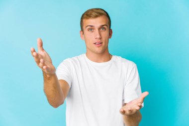 Genç, beyaz, yakışıklı adam kollarıyla ölçü yapıyor, mutlu ve kendinden emin..