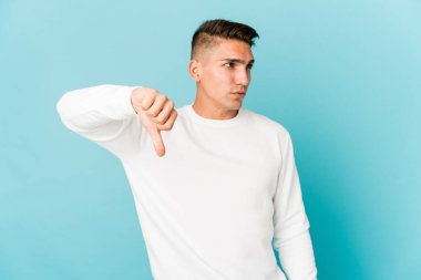 Genç, beyaz, yakışıklı, izole edilmiş, baş parmağını aşağı gösteren ve hoşlanmadığını ifade eden bir adam..