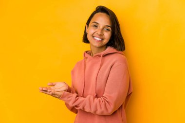 Sarıda izole edilmiş genç İspanyol kadın avucunun içinde bir kopya alanı tutuyor..