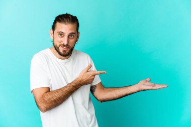 Uzun saçlı genç adam, elinde bir fotokopi odası tutarken heyecanlı görünüyor..