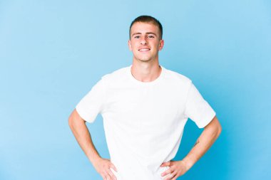 Beyaz tenli yakışıklı, kendine güveni tam. Ellerini kalçasından ayırmıyor..