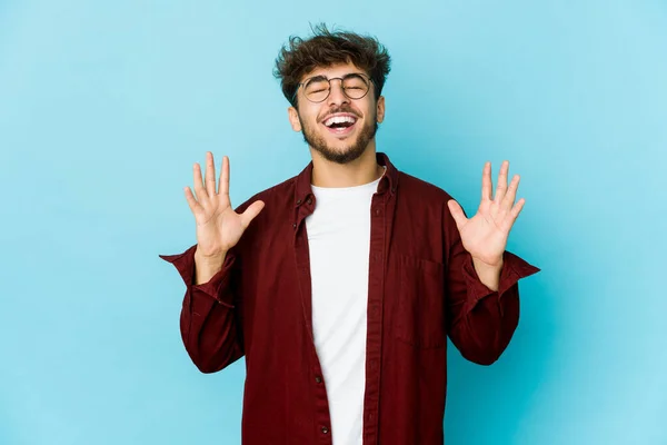 Ung Arabisk Man Blå Bakgrund Skrattar Högt Hålla Handen Bröstet — Stockfoto