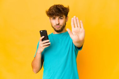 Genç Hindistanlı bir adam, elinde bir telefonla dur işareti göstererek seni engelliyor..
