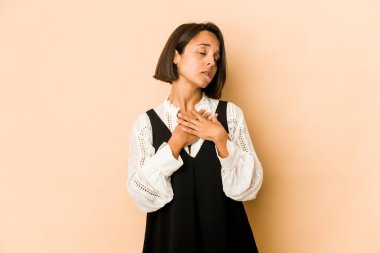 İzole edilmiş genç İspanyol kadın, dost canlısı bir ifadeye sahip, avuçlarını göğsüne bastırıyor. Aşk konsepti.