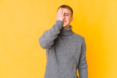 Beyaz tenli yakışıklı adam yüzünün yarısını palmiyeyle örterek eğleniyor..