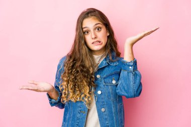 Kafası karışmış genç beyaz bir kadın, bir kopya alanı tutmak için omuz silkiyor..