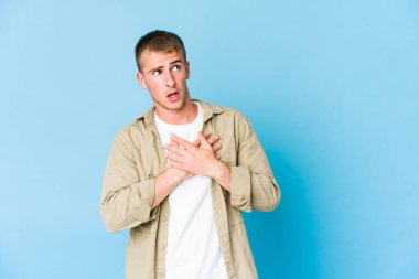 Beyaz tenli yakışıklı bir adam dost canlısı bir ifadeye sahip, avuçlarını göğsüne bastırıyor. Aşk konsepti.