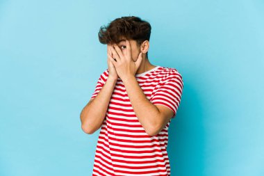 Mavi arka plandaki genç Arap parmaklarıyla gözünü kırp korkmuş ve gergin.