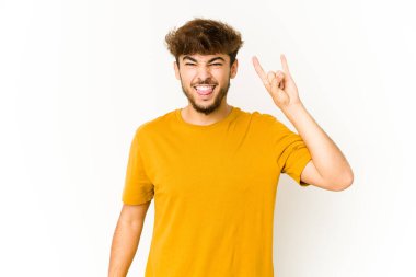 Beyaz arka planda genç bir Arap, parmaklarıyla kaya hareketi gösteriyor.