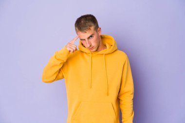 Genç, beyaz, yakışıklı bir adam şakağı parmağıyla işaret ediyor. Düşünüyor, bir göreve odaklanıyor..