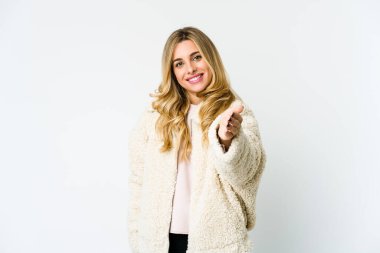 Beyaz tenli sarışın kadın selamlama jesti olarak kameraya elini uzatıyor..