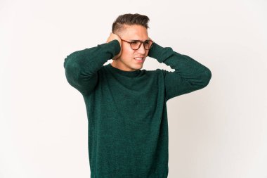 Genç, beyaz, yakışıklı bir adam, izole edilmiş kulakları elleriyle kapatıyor..