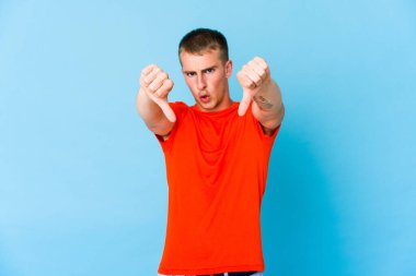 Beyaz tenli yakışıklı adam baş parmağını aşağı gösteriyor ve hoşlanmadığını söylüyor..