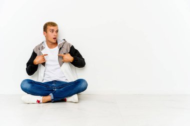 Yerde oturan genç, beyaz bir adam parmağını göstererek şaşırdı ve gülümsedi..