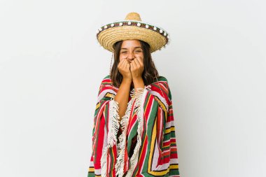 Beyaz arka planda izole edilmiş genç Meksikalı bir kadın bir şeye gülüyor, elleriyle ağzını kapatıyor..