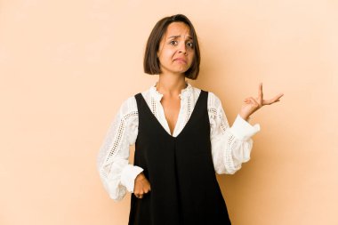 Latin kökenli genç bir kadın kuşkuyla hareket ederek omuz silkiyor..