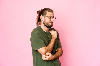 Uzun saçlı genç adam şaşkın, kuşkulu ve kararsız görünüyor..