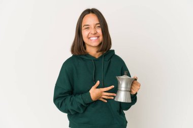 Genç İspanyol kadın elinde kahve makinesiyle gülüyor ve eğleniyor..