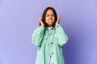 Genç melez kadın kulaklarını parmaklarıyla kapatıyor, gürültülü bir ortam yüzünden stresli ve çaresiz..