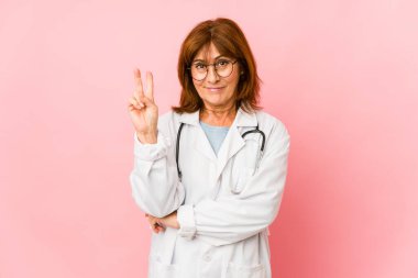 Orta yaşlı beyaz doktor kadın izole edilmiş. İki numarayı parmaklarıyla gösteriyor..