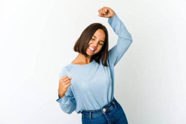 Genç melez kadın özel bir günü kutluyor, atlıyor ve enerjiyle kollarını kaldırıyor..