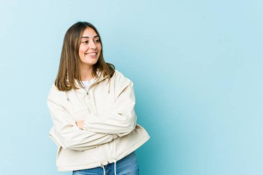 Genç beyaz kadın kollarını kavuşturarak gülümsüyor..