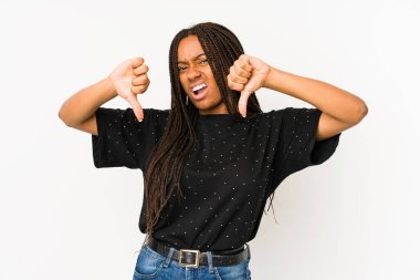 Beyaz arka planda izole edilmiş genç Afrikalı Amerikalı kadın baş parmağını aşağı gösteriyor ve hoşlanmadığını ifade ediyor..