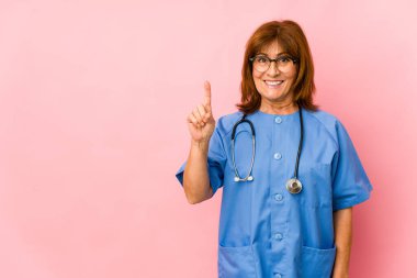 Orta yaşlı, beyaz bir hemşire. Bir numarayı parmağıyla gösteriyor..