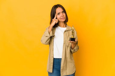 Elinde bir ödül heykeli tutan genç İspanyol kadın parmağıyla tapınağı işaret ediyor, düşünüyor ve bir göreve odaklanıyor..