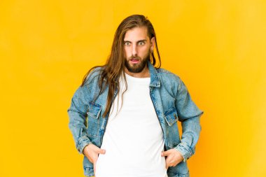 Uzun saçlı genç adam bir şey yüzünden şoka girmiş gibi görünüyor.