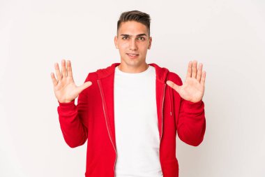 Beyaz tenli yakışıklı bir adam kendini izole etmiş, işaret parmaklarıyla küçük bir şey tutuyor, gülümsüyor ve kendinden emin..