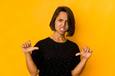 Sarıda izole edilmiş genç İspanyol kadın baş parmağını aşağı gösteriyor ve hoşlanmadığını ifade ediyor..