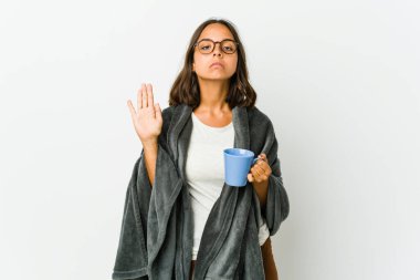 Beyaz arka planda battaniyeli genç Latin kadın yemin ediyor, elini göğsüne koyuyor..