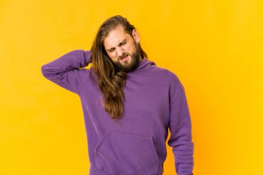 Uzun saçlı genç adam başının arkasına dokunuyor, düşünüyor ve bir seçim yapıyor..